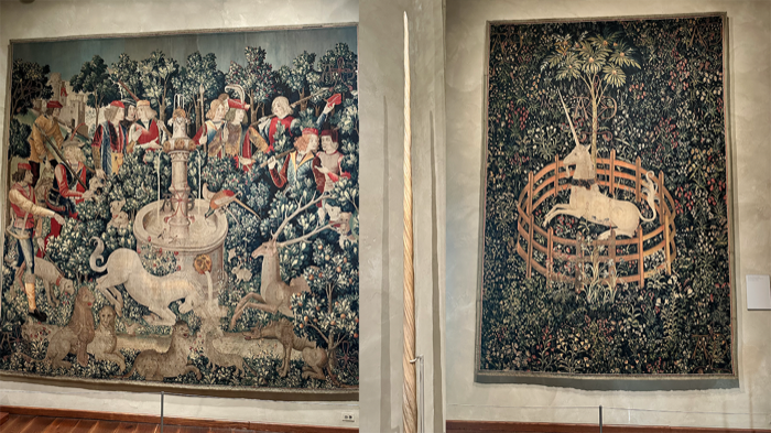 Two medieval tapestries: left shows a unicorn hunt with figures and animals, right depicts a unicorn in a walled garden. Between them, a narwhal tusk.