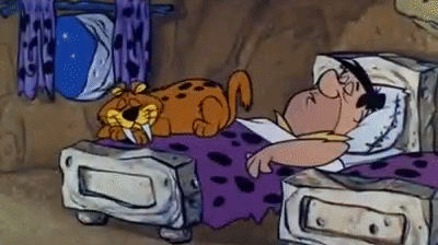 Cartoon man (Fred Flintstone) snoring so strongly that the cat flies off the bed