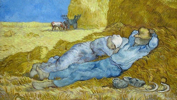 Two people resting on hay in a field under clear blue sky, with oxen and cart in the background
